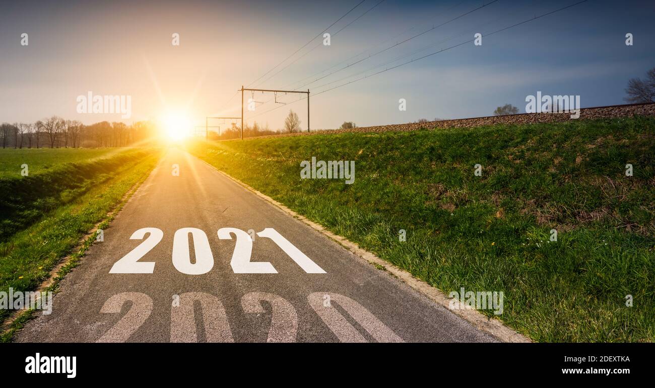 Neujahrskonzept mit dem Jahr 2021, das`s der Mitte einer Asphaltstraße bei Sonnenuntergang gedruckt wird. Stockfoto